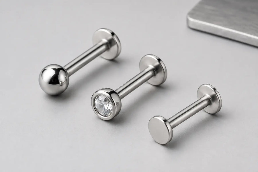 Illustrative close-up of polished titanium flat-back labrets showing the shafts, bases and surface finish.